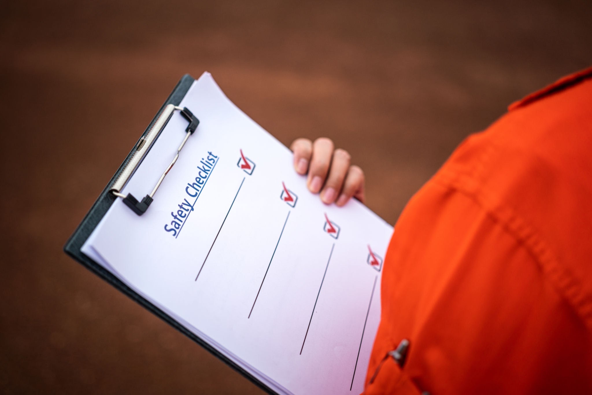 A blank safety checklist form on safety officer or operation supervisor hand, preparing to perform safety audit at construction workplace. Industrial safety working concept scene, selective focus.